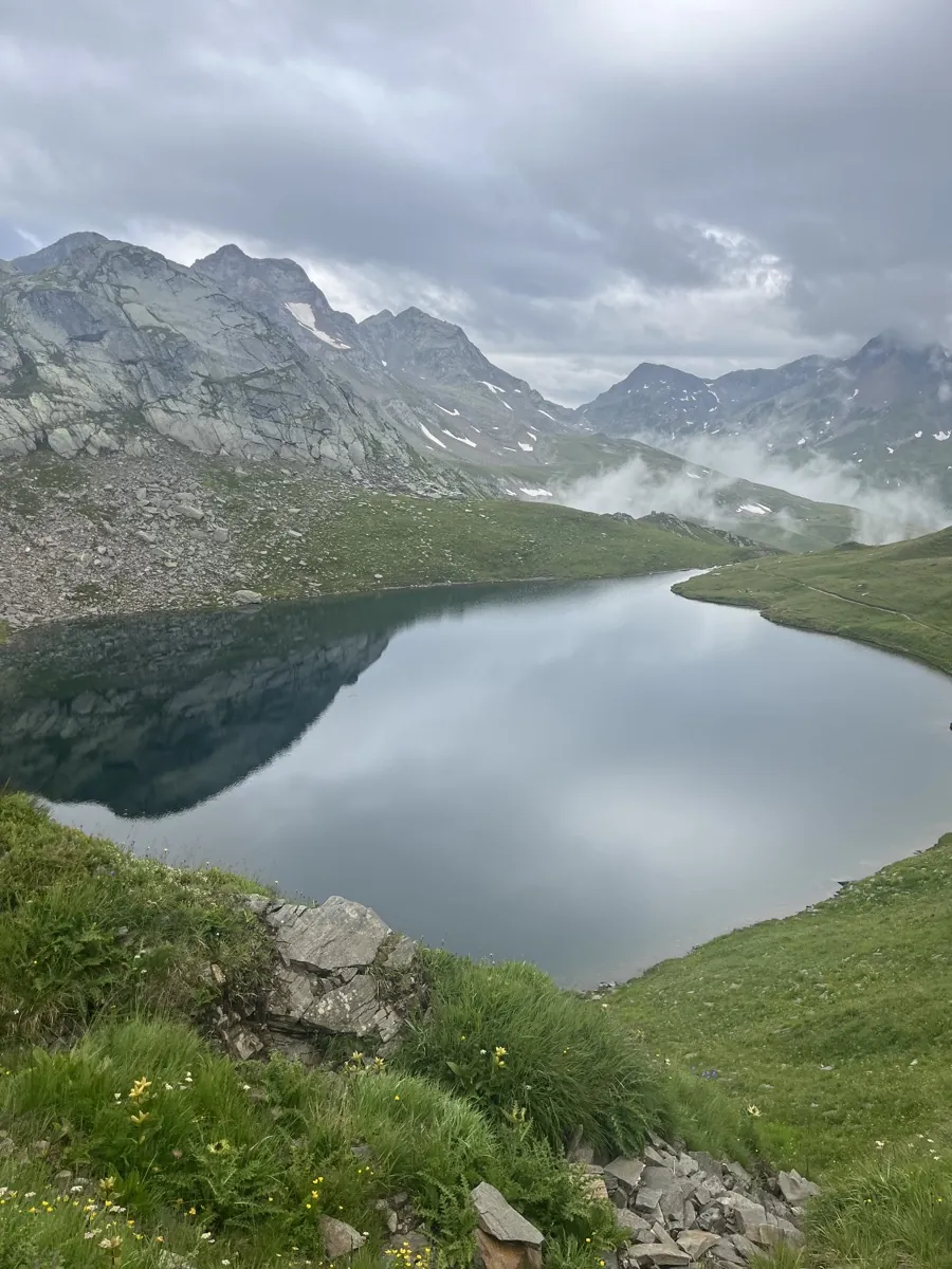 Mountain lake surrounded by green slopes and cloud-covered peaks